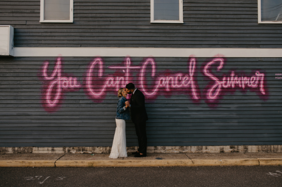 bride and groom pose outside by graffiti